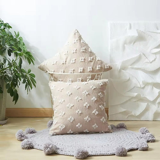 Funda de cojín beige con figuras en relieve.