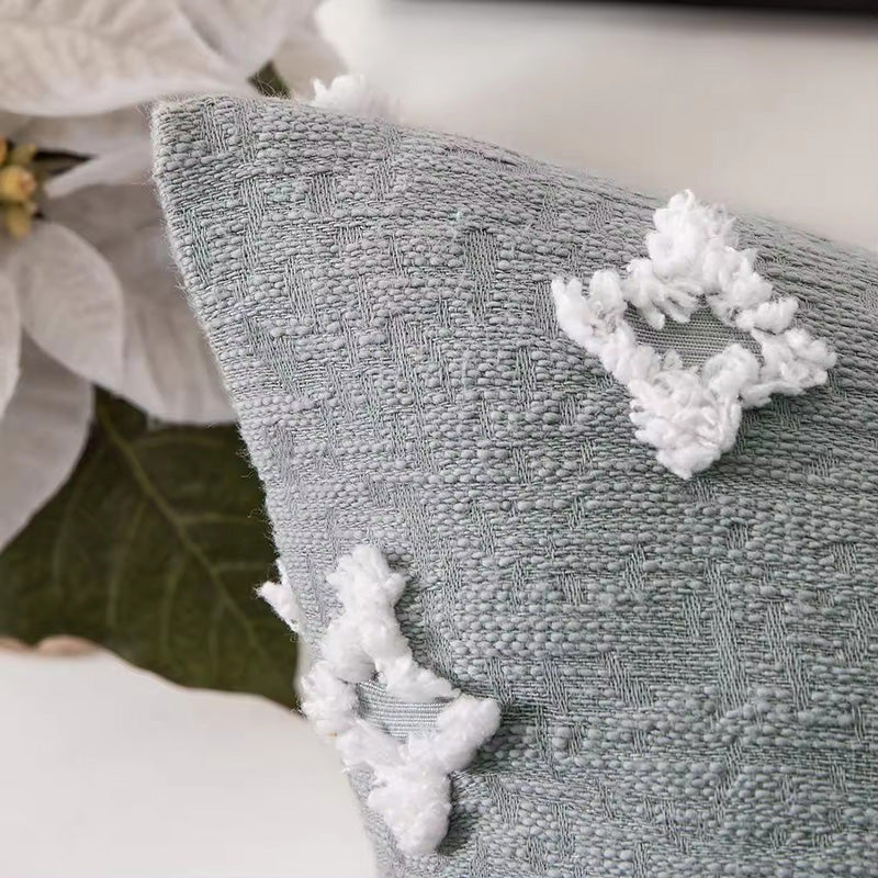 Funda de cojín gris verdoso claro con figuras en relieve.