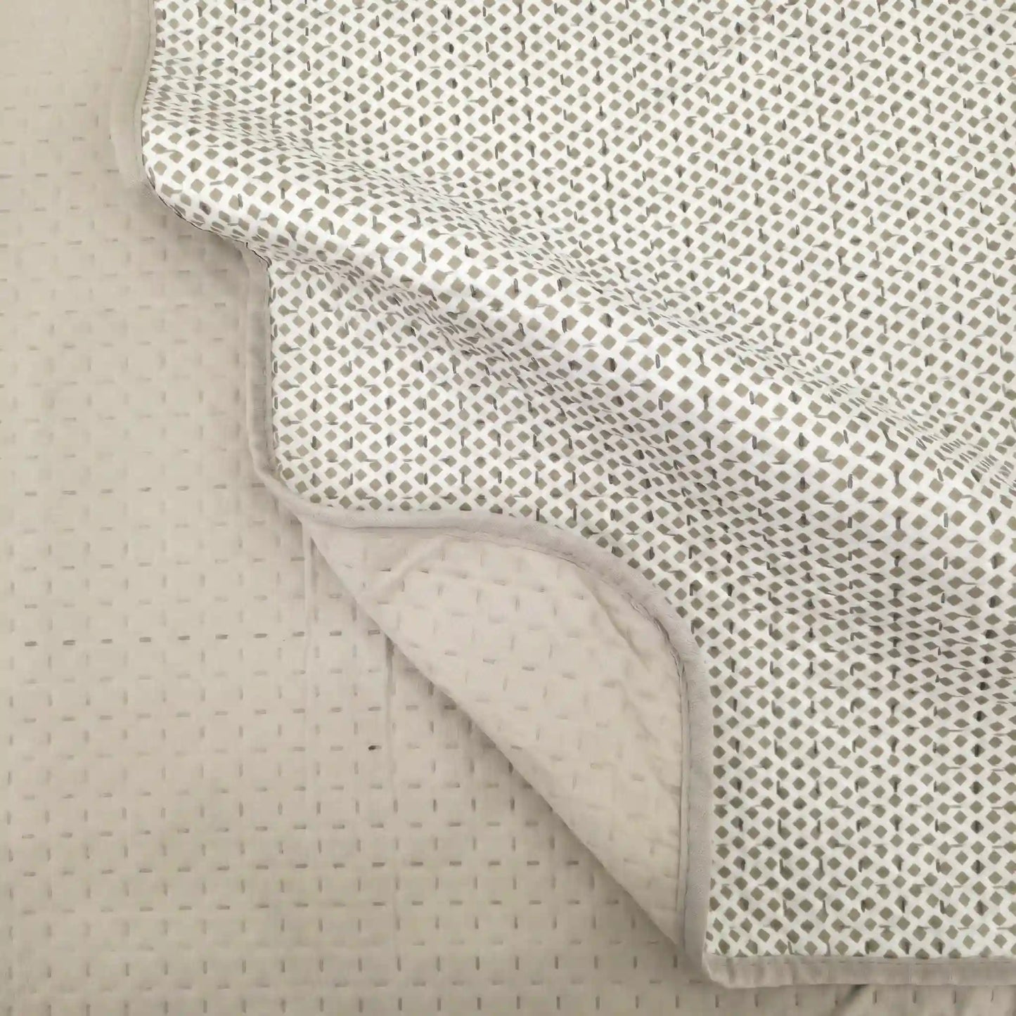 Detalle de las esquinas redondeadas y caída de la colcha de verano beige en la cama