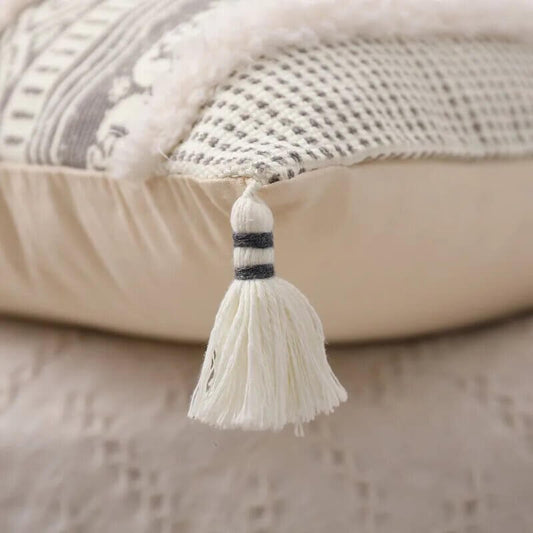 Funda de cojín boho étnico en blanco y gris claro con flecos.