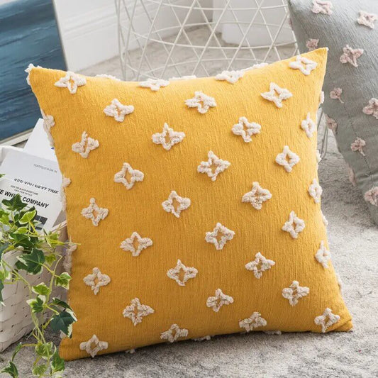 Funda de cojín mostaza con figuras en relieve.