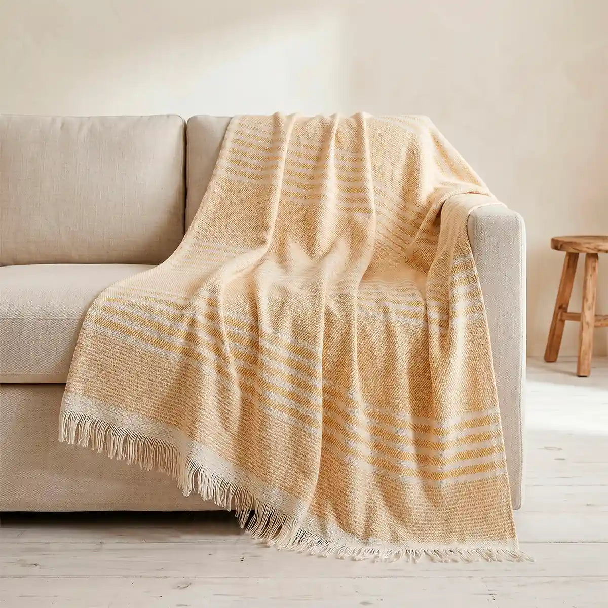 Colcha de verano multiusos de rayas amarillas y crudas extendida sobre una cama. Fabricada en algodón sostenible transpirable.