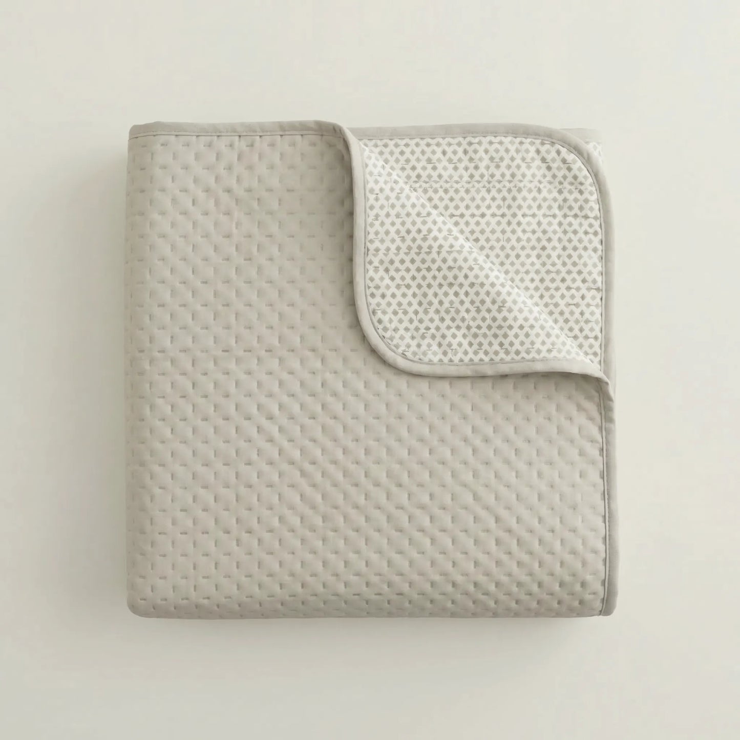 Detalle del tejido fino, acolchado y costuras de la colcha bouti beige