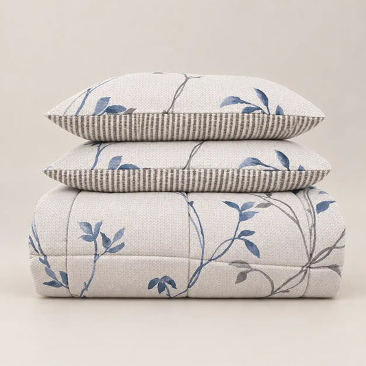 Piumone invernale con stampa floreale blu e retro a righe, piegato ordinatamente con due federe abbinate.