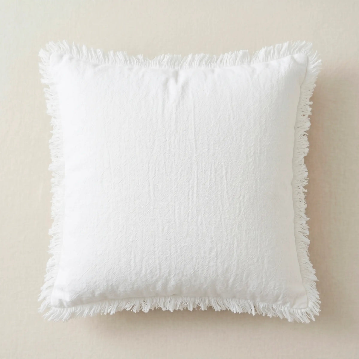 Funda de cojín blanca 45x45cm de 100% algodón con detalles de flecos de Oma Home. Diseño puro y luminoso para sofá.