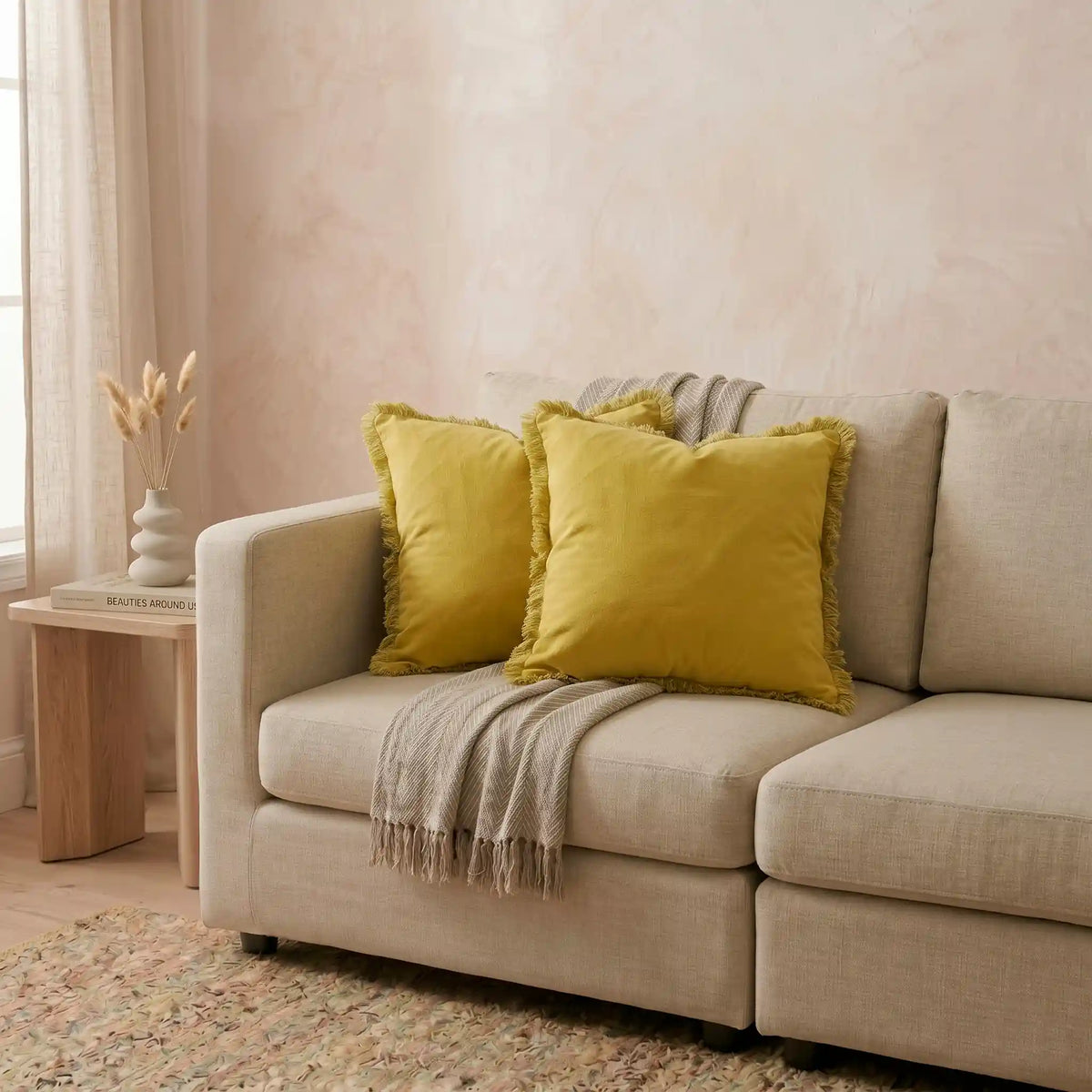 Funda de cojín mostaza con flecos de Omahome decorando un sofá, aportando luz y un toque vibrante al salón.