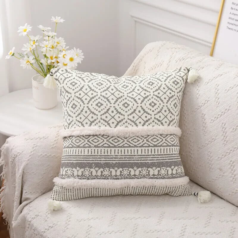 Funda de cojín boho étnico en blanco y gris claro con flecos.