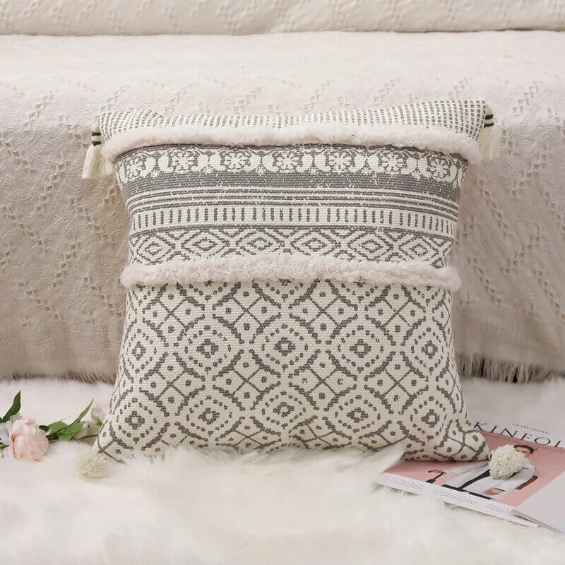Funda de cojín boho étnico en blanco y gris claro con flecos.